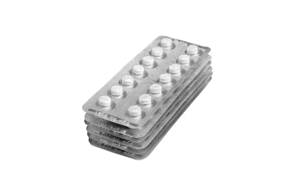 Smärtstillande läkemedel och koffein illustreras av en stapel med tablettkartor som visar receptfria värktabletter mot huvudvärk.