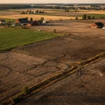 Flygbild över torra jordbruksmarker i Skåne med bevattningsutrustning