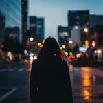 Siluett av ung kvinna mot urban bakgrund i skymning