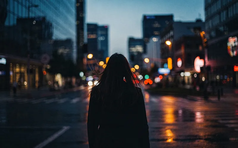 Siluett av ung kvinna mot urban bakgrund i skymning