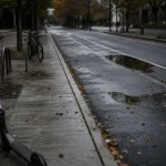 Tom cykelväg i stad med en elsparkcykel parkerad vid trottoarkanten